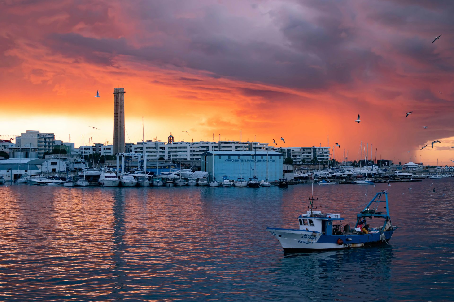 Festa in barca in Puglia con gruppo di amici durante il tramonto sul mare