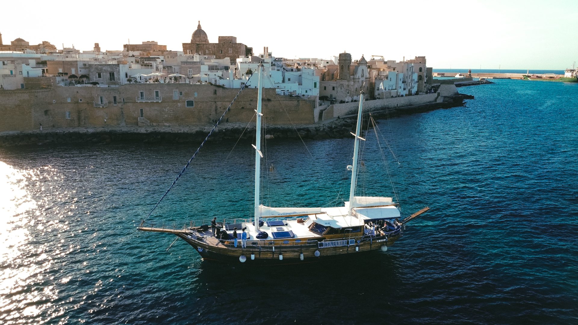Coppia che brinda durante un'esperienza romantica in barca al tramonto lungo la costa della Puglia